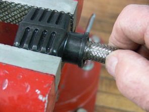 Twist the braided stainless steel hose into the funnel of the hose assembly tools
